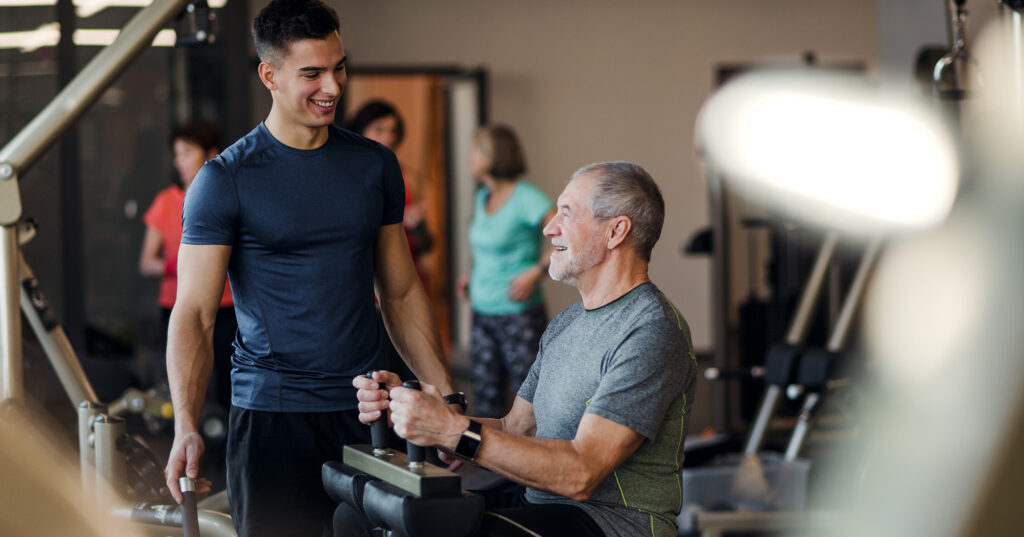Personal fitnesstrainer en oudere man die een speciaal sportprogramma afwerken.